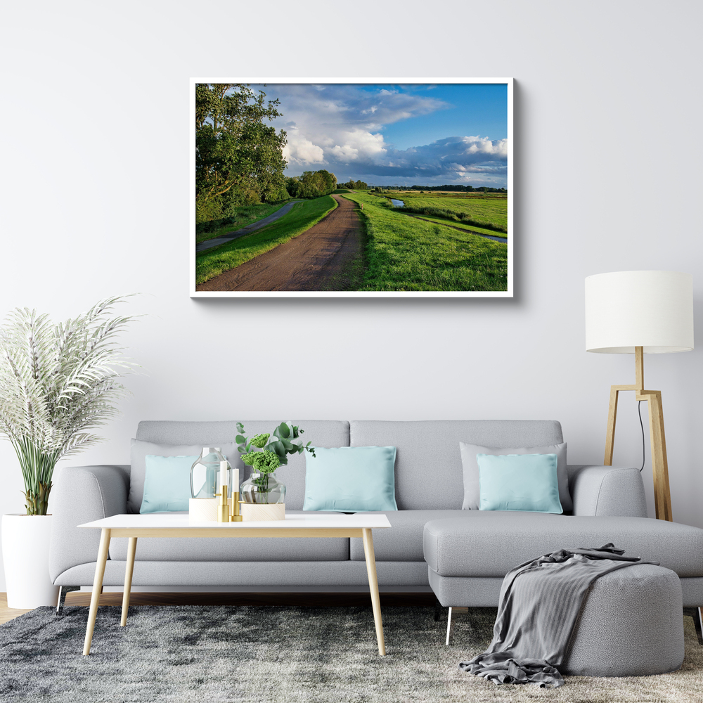 Foto de paisaje en metacrilato con marco blanco sobre un sofá gris en un salón luminoso