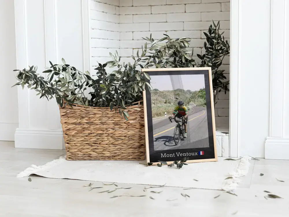 Foto de ciclismo enmarcada con lugar, apoyada en el suelo junto a una planta, un regalo para ciclistas