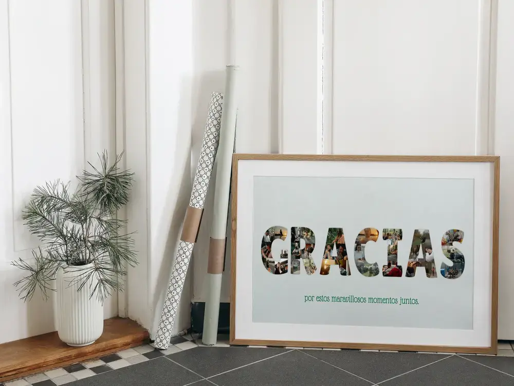 Póster de agradecimiento con letras formadas por fotos, enmarcado en madera y apoyado en el suelo junto a una planta