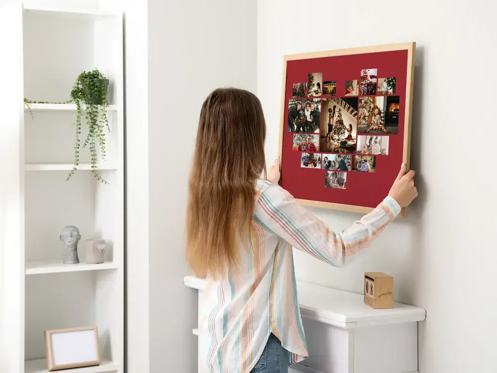 Collage de fotos en corazón sobre rojo oscuro, con marco en pared clara, un detalle navideño para la familia