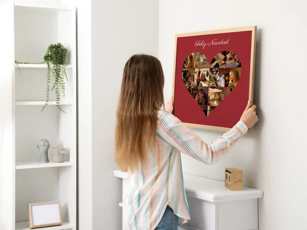 Regalo de Navidad: collage de fotos en forma de corazón sobre fondo rojo, con marco de madera clara en la pared