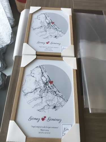 Dos pósteres de mapas urbanos circulares con corazón y marco de madera natural sobre una mesa, regalo romántico